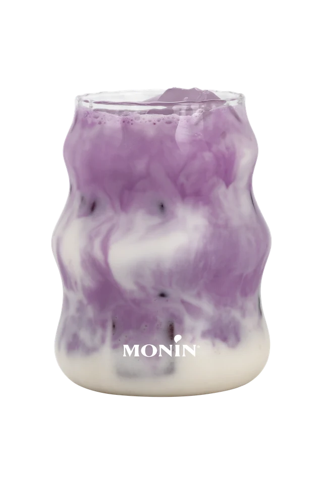 Mramorované fialové Ube latte s liči na průhledném pozadí.